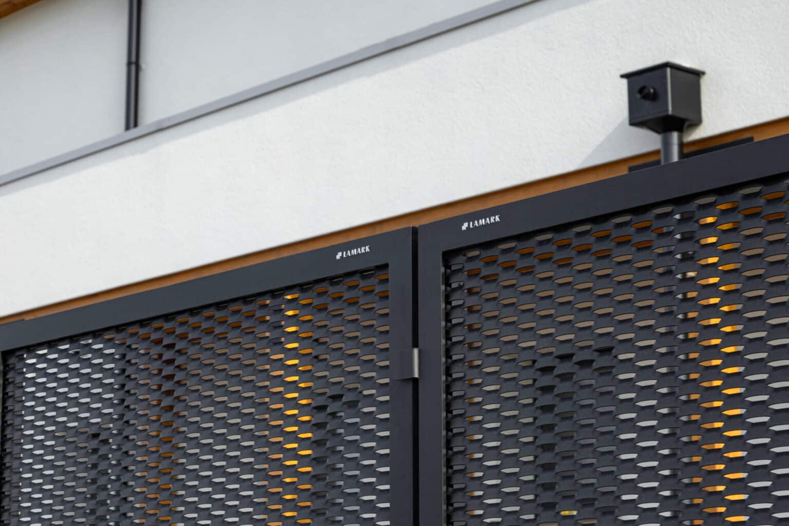 Detail loga LAMARK na samonosných posuvných bránách LAMARK z tahokovu | Motiv Madeira | Černá kovářská barva | Zděné sloupky