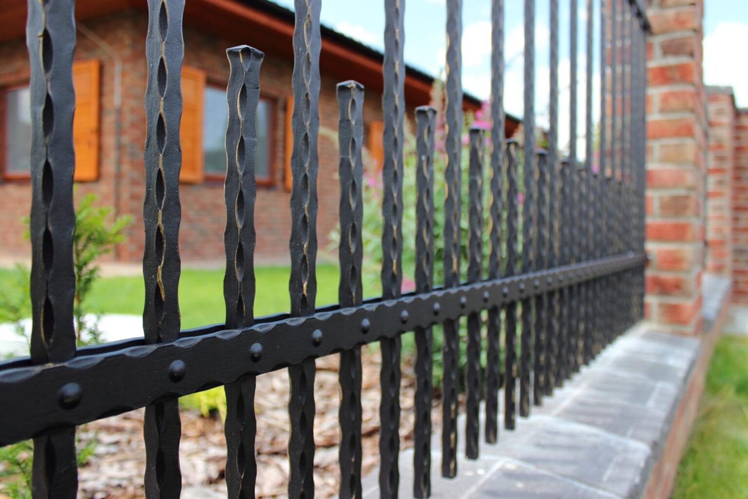 Detail dekoru mezipříčky na kovaném plotě LAMARK | motiv Verona | Oklepávané provedení | Okované konce | Zlatá patina | Svařované s nýty | Černá kovářská barva