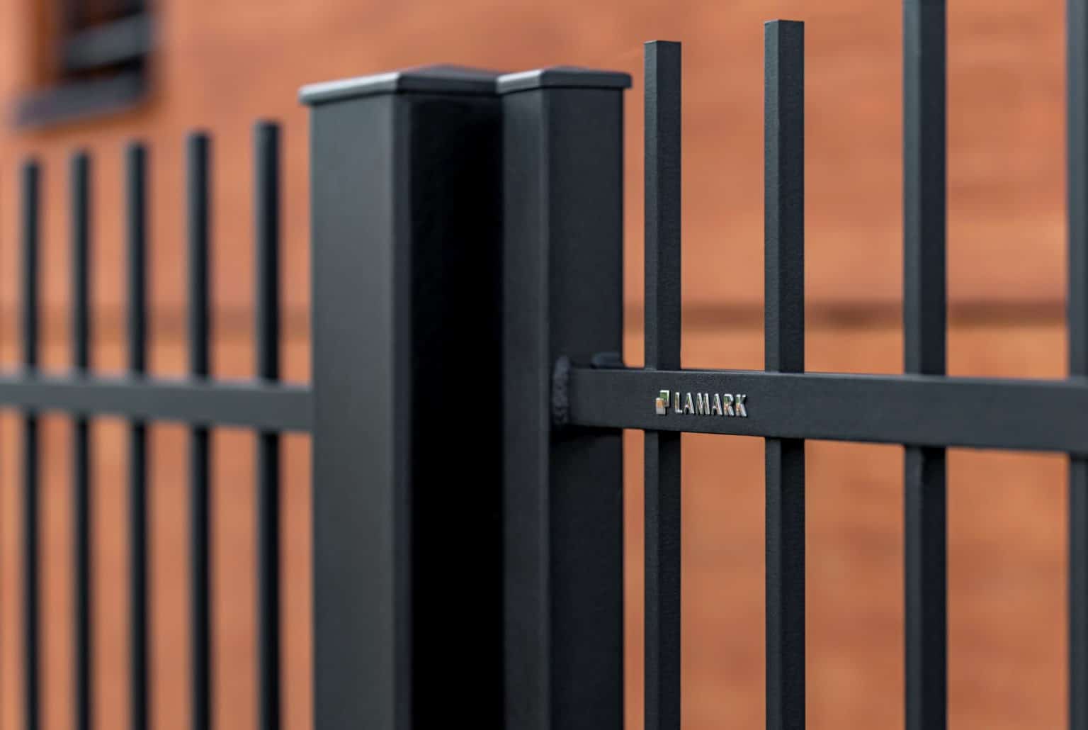Detail loga na kované jednokřídlé brance LAMARK | Motiv Miami | Motiv Portoriko | Hladké provedení | Bez nýtů | Rovné zakončení | Šedá antracitová barva | Hliníkové sloupky LAMARK