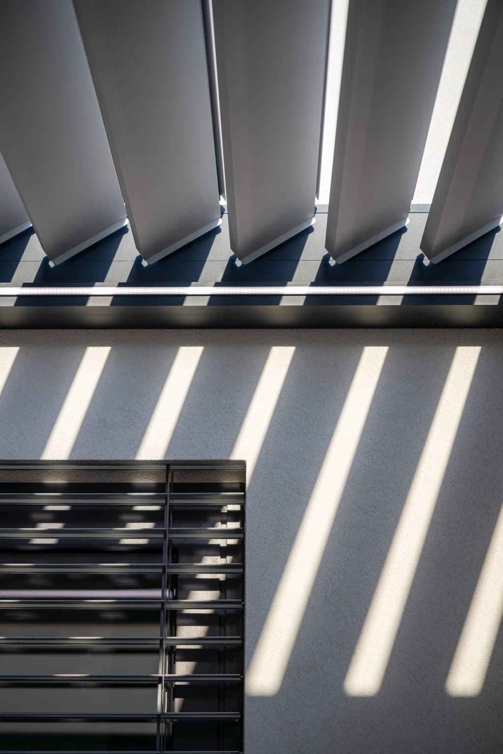 Detail lamel bioklimatické pergoly LAMARK | Pergola přisazená ke stěně | Předměřice nad Labem | Boční stínění - screenové rolety | Šedá antracitová barva | Dešťové čidlo | Větrné čidlo | Ovládání