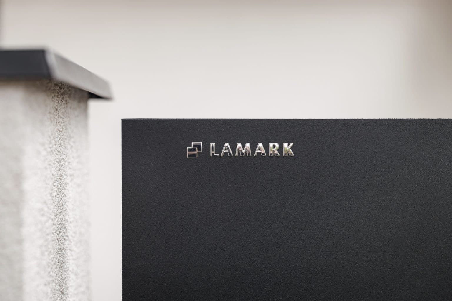 Detail loga LAMARK | Deskový plot LAMARK | Motiv Sora | Černá kovářská barva | Zděné sloupky