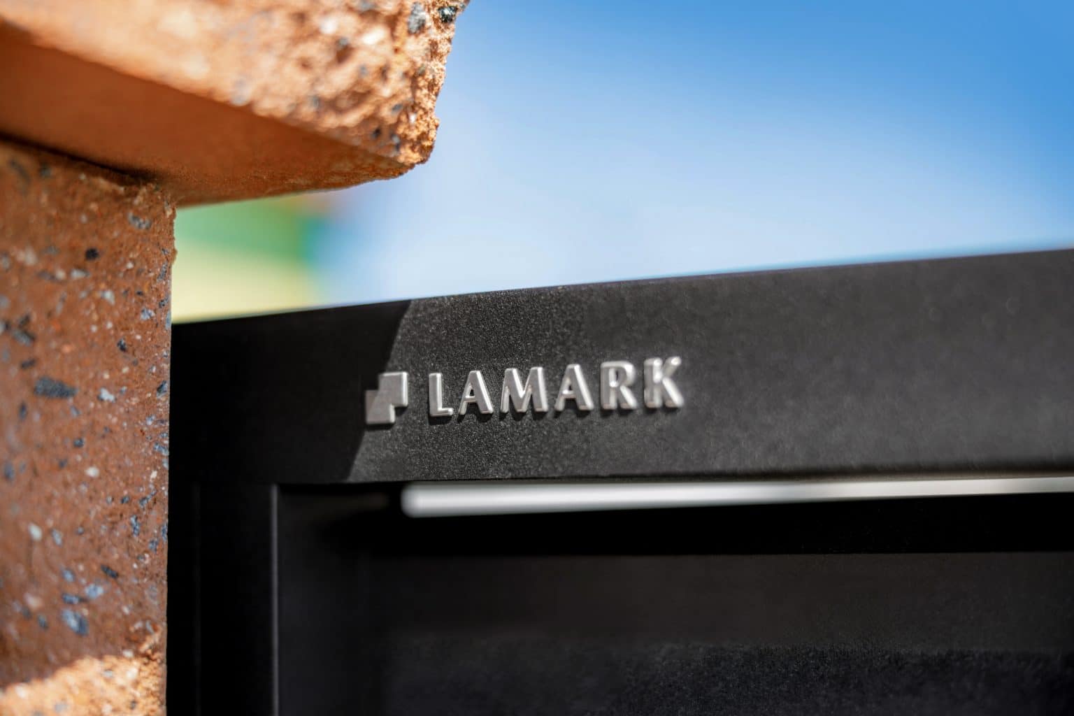 Detail loga LAMARK na hliníkové bráně | Motiv Lugo Air | Černá kovářská barva | Betonové sloupky