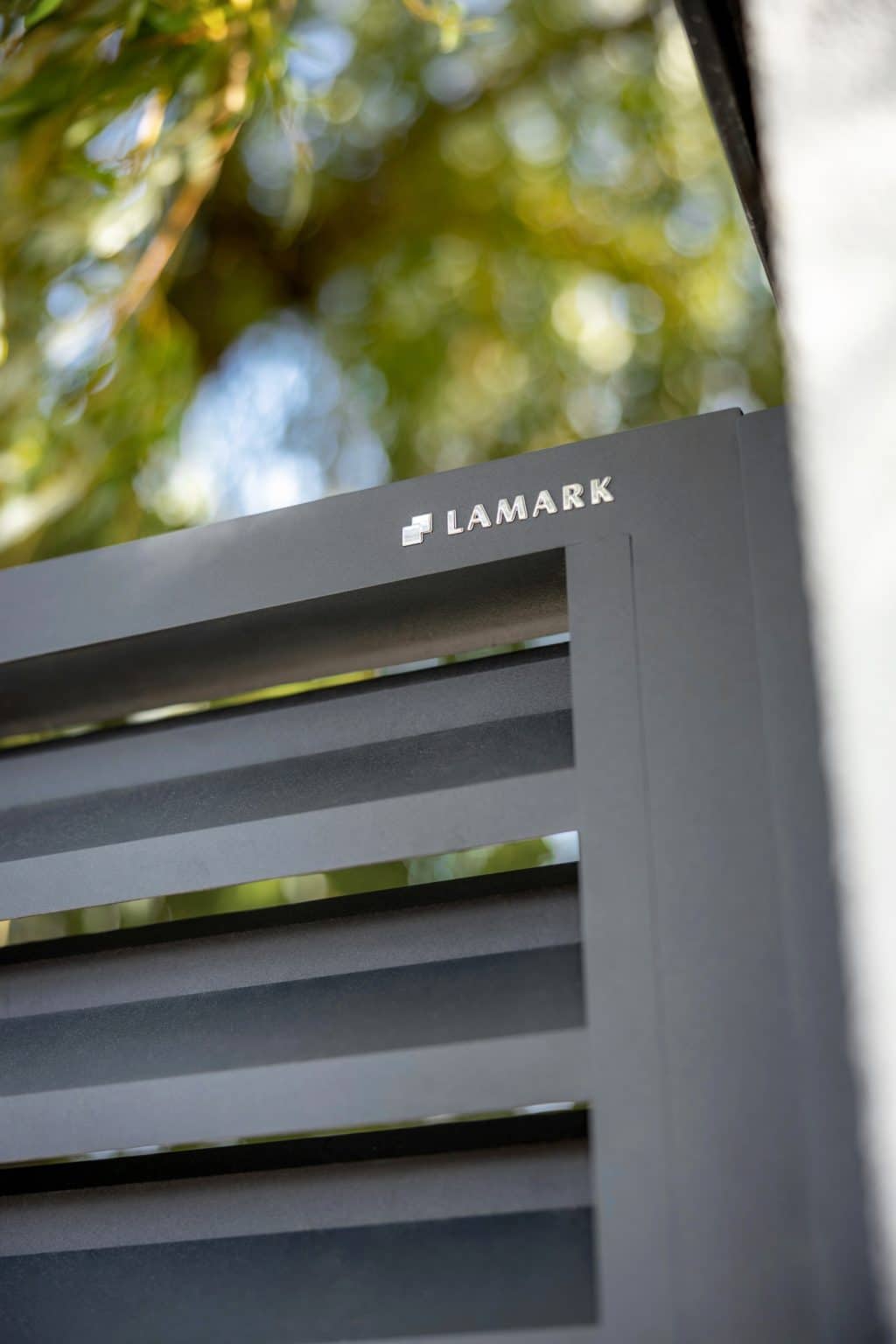 Detail loga LAMARK na hliníkové jednokřídlé brance | Motiv Lugo | Šedá antracitová barva | Zděné sloupky