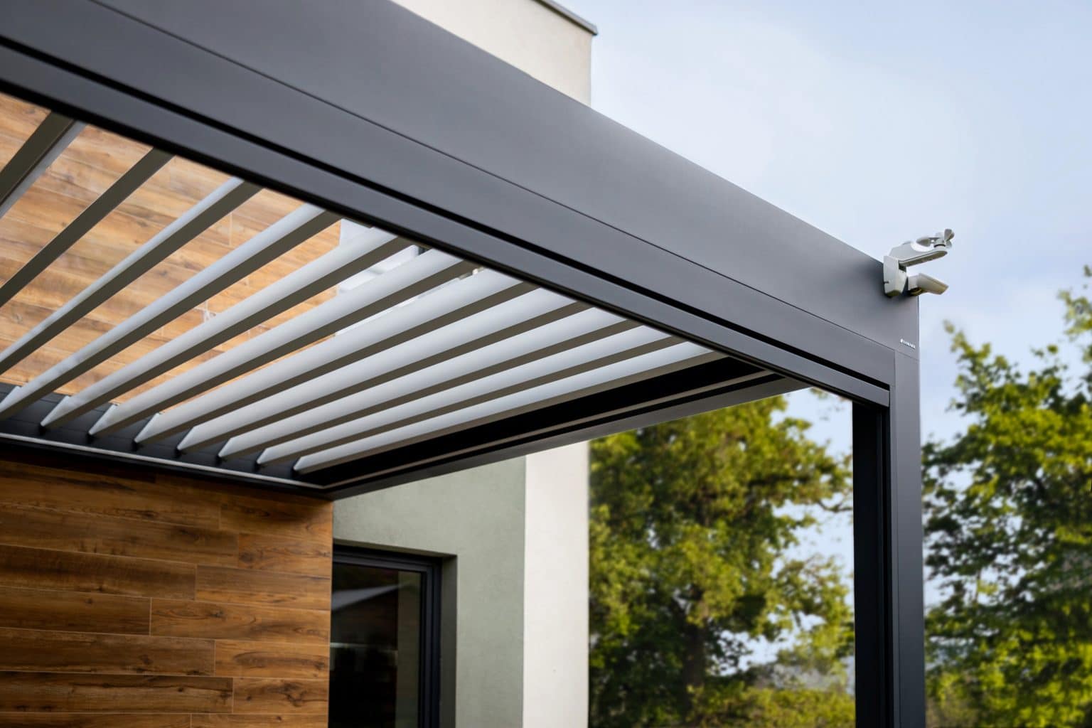 Detail bioklimatické pergoly LAMARK přisazené ke stěně | Chotěboř | Boční stínění - screenové rolety | Černá kovářská barva | Dešťové čidlo | Větrné čidlo | Ovládání | LED osvětlení