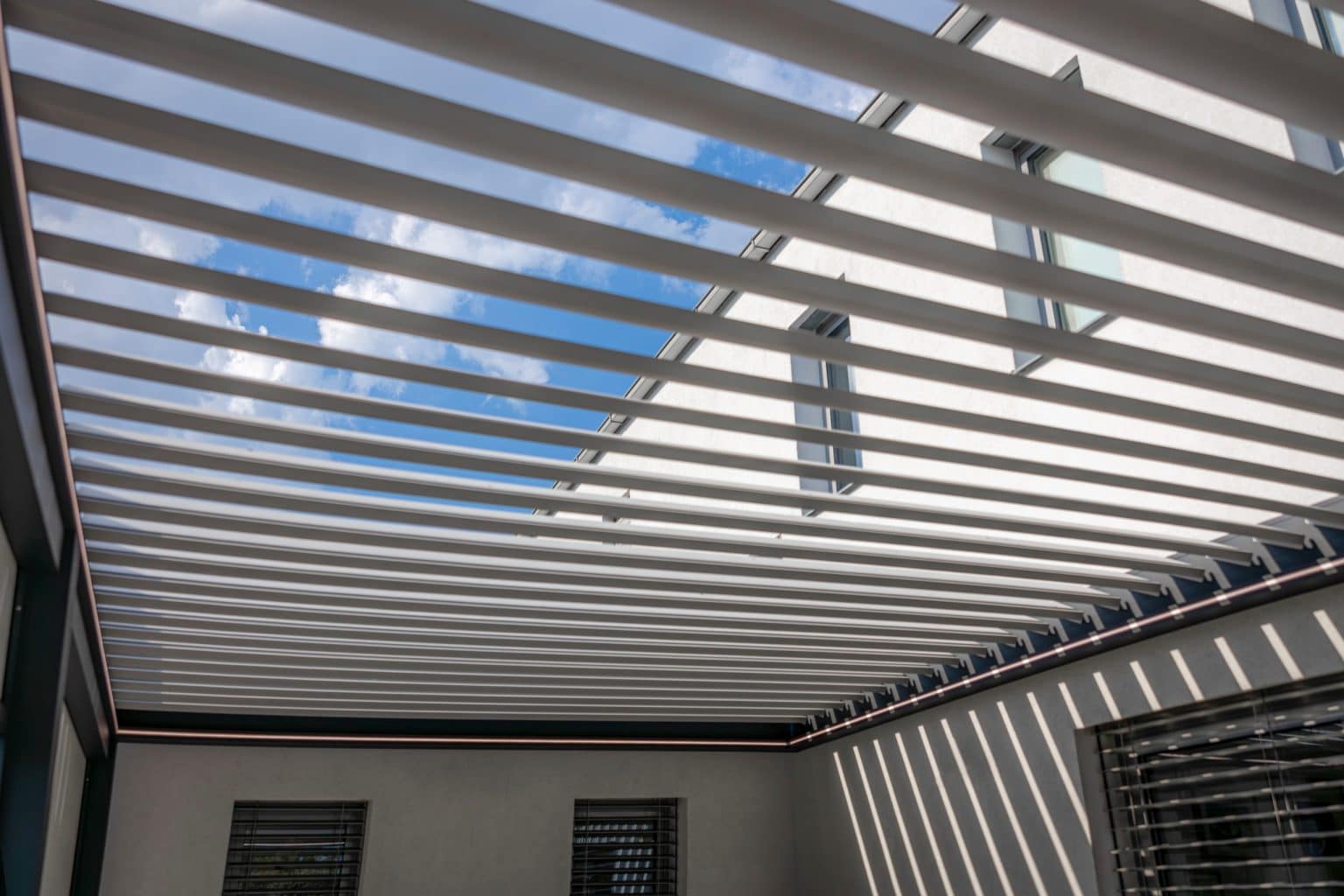 Detail lamel bioklimatické pergoly LAMARK přisazené ke stěně | Pátek | Boční stínění - screenové rolety | Šedá antracitová barva | LED osvětlení