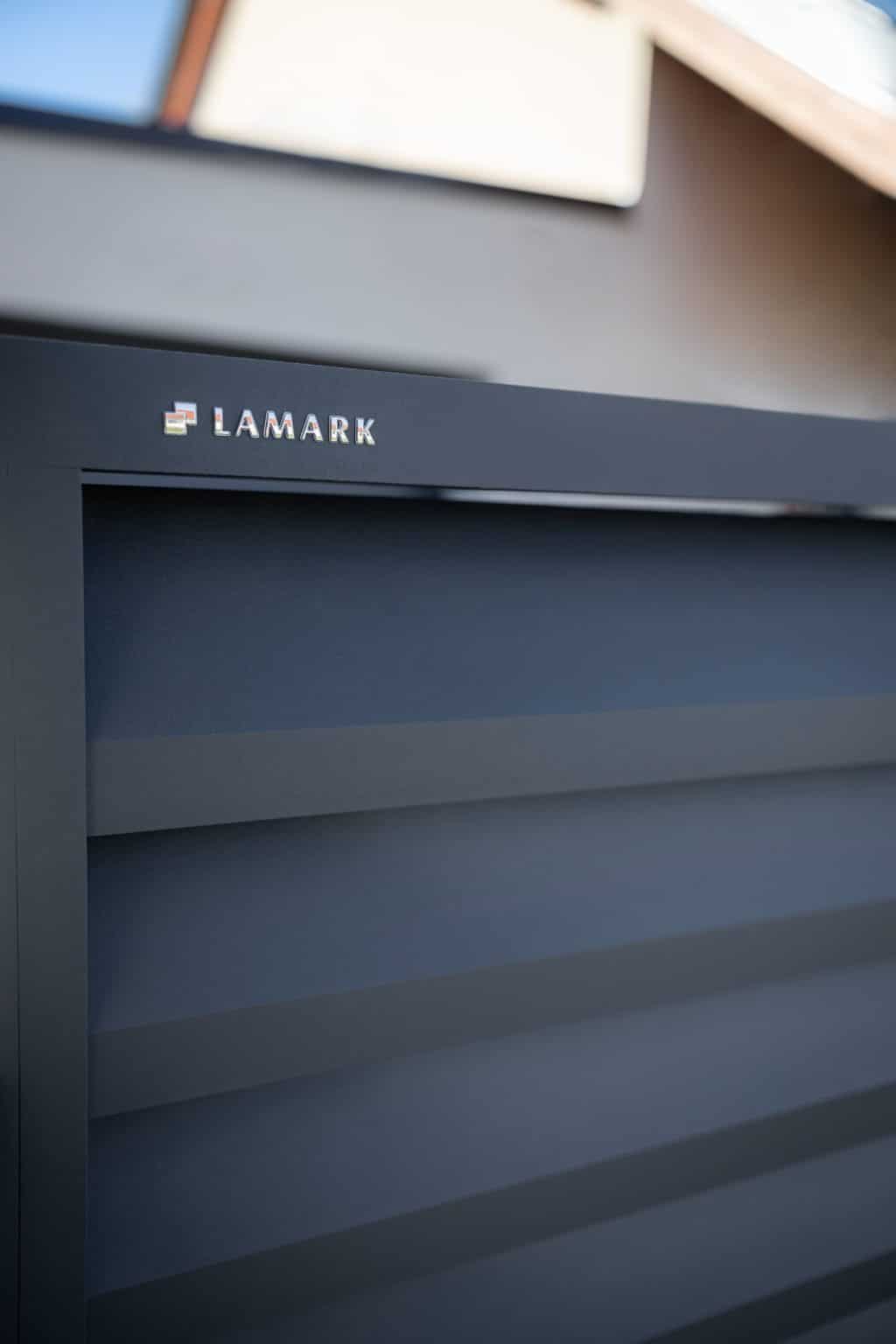 Detail loga LAMARK na hliníkovém plotě | Motiv Alicante | Šedá antracitová barva | Zděné sloupky