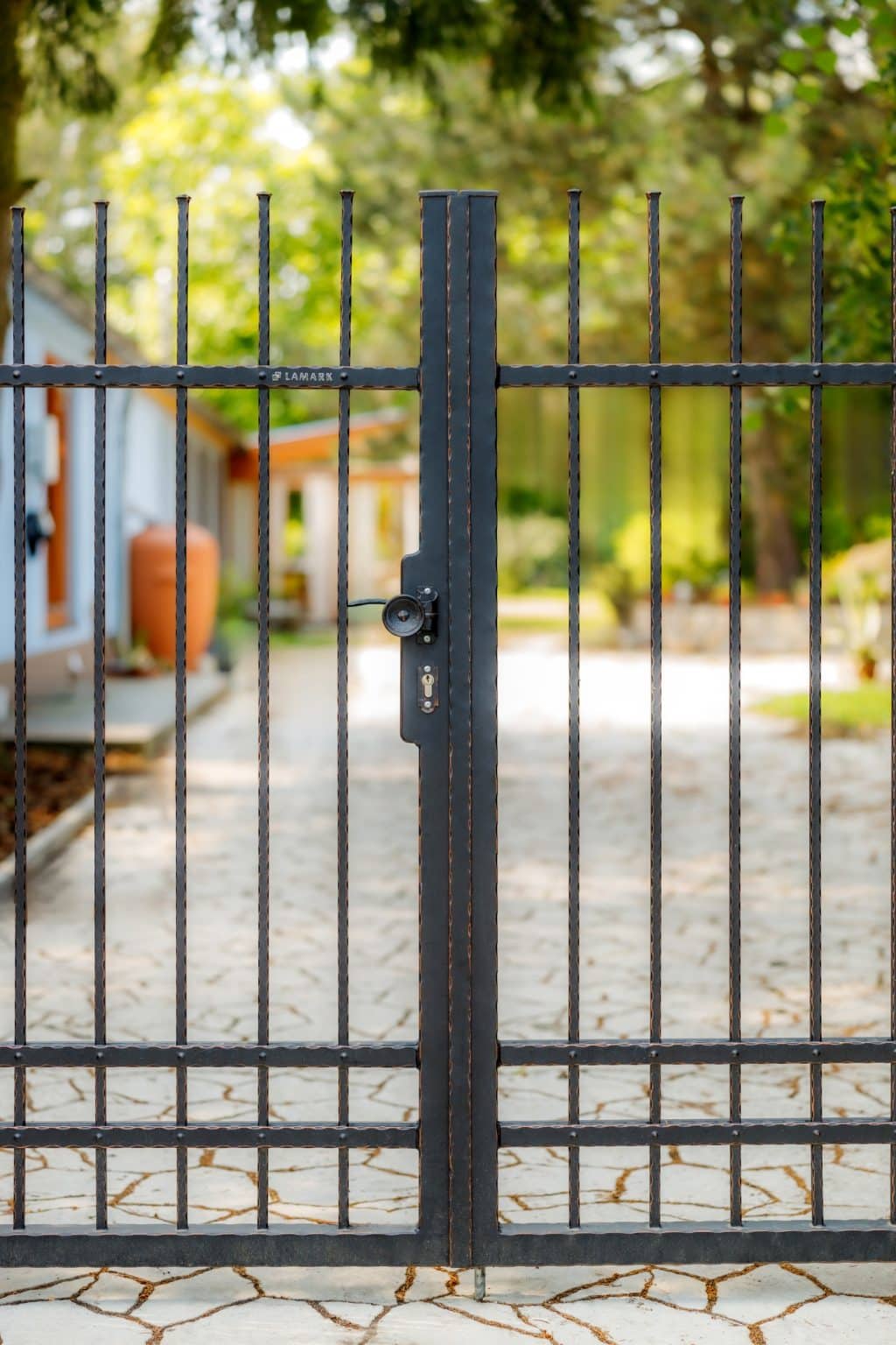 Detail kované dvoukřídlé otočné brány LAMARK s ručním otevíráním | Motiv Detroit | Černá kovářská barva | Měděná patina | Svařované s nýty | Oklepávané provedení | Okované konce | Zděné sloupky