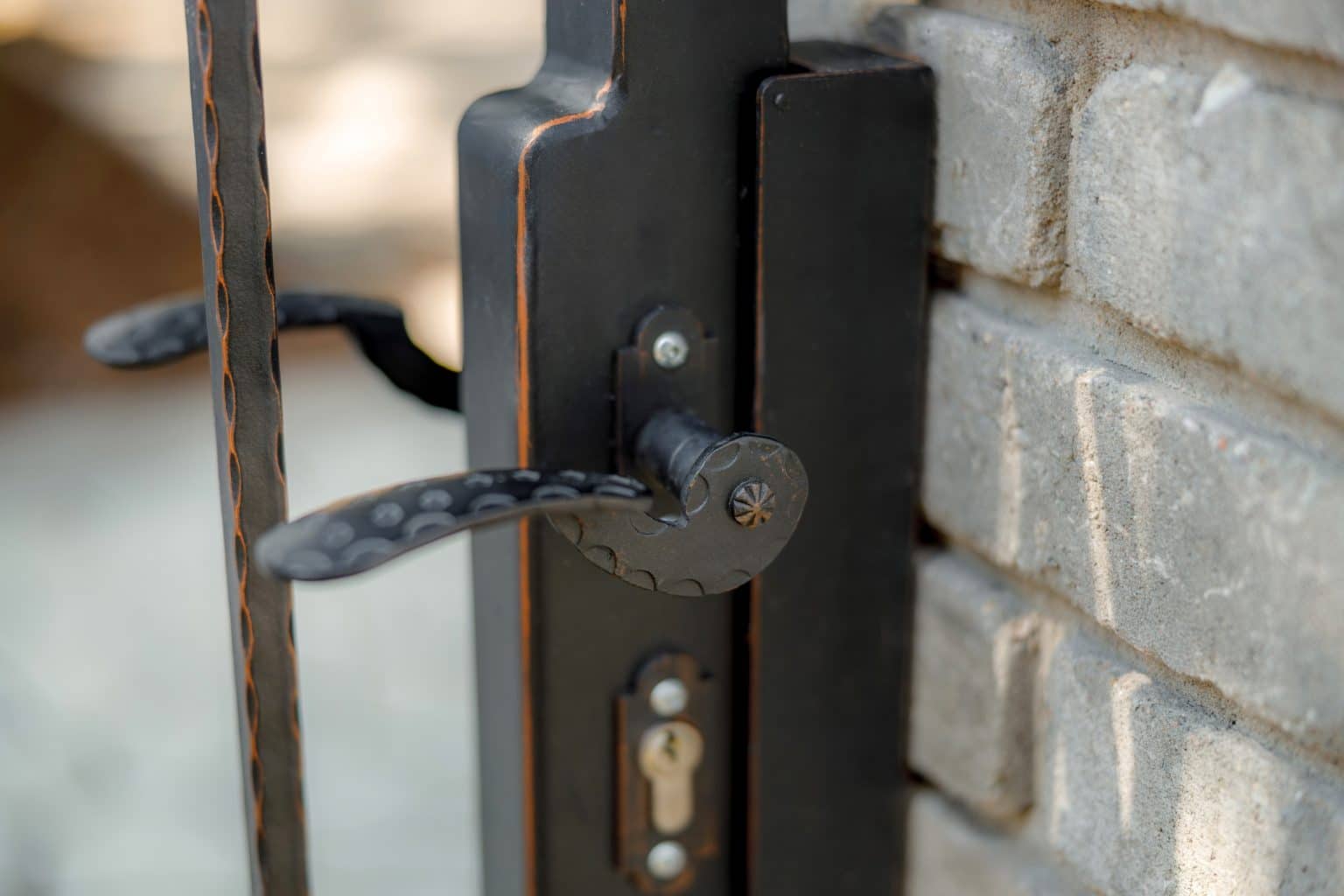 Detail kliky na kované brance LAMARK | Motiv Detroit | Černá kovářská barva | Měděná patina | Svařované s nýty | Oklepávané provedení | Okované konce | Zděné sloupky