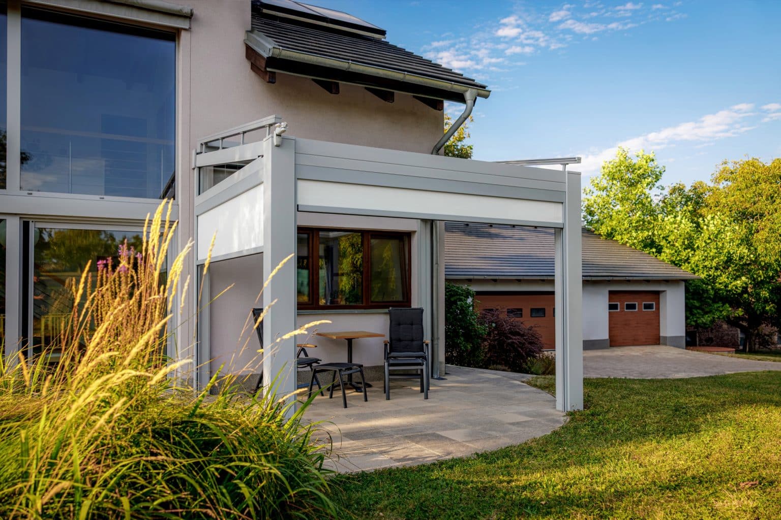 Pergola LAMARK se skleněnou střechou přisazená ke stěně | Stříbrná hliníková barva | Screenové rolety | Větrné čidlo | LED osvětlení